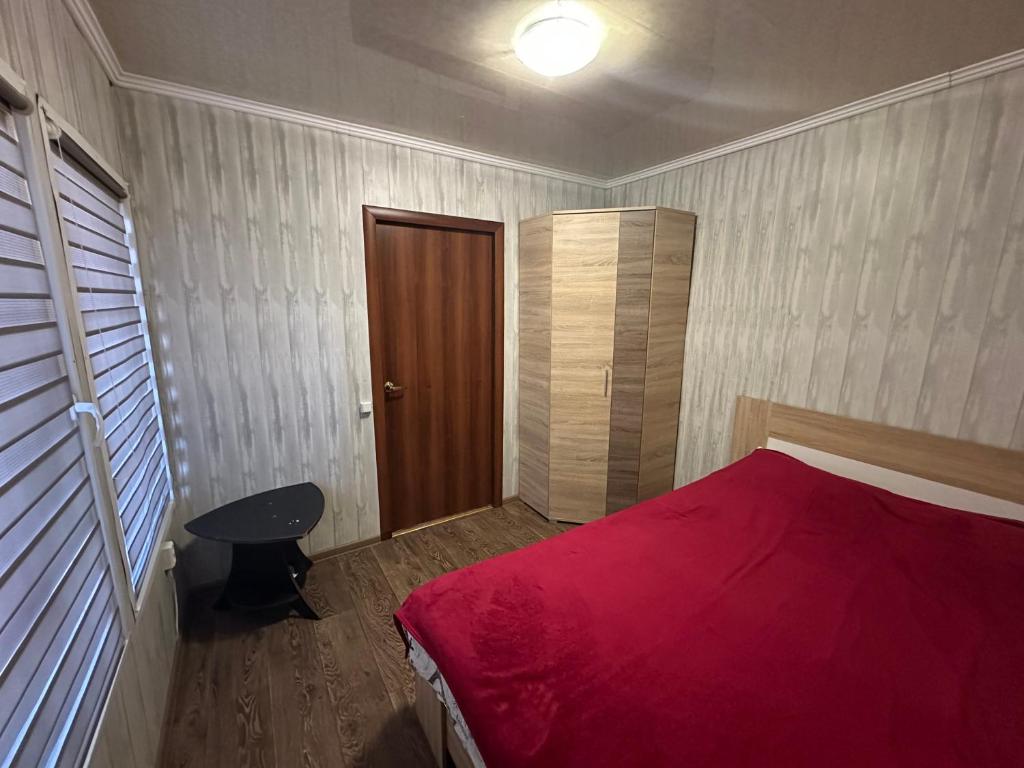 a bedroom with a red bed and a wooden door at домик у самого моря in Odesa