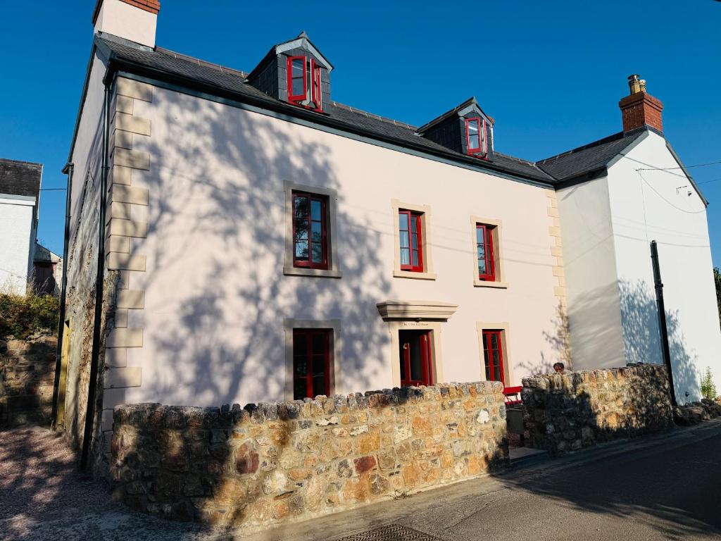 a white house with red windows and a stone wall at The Old Manse, Horton in Horton