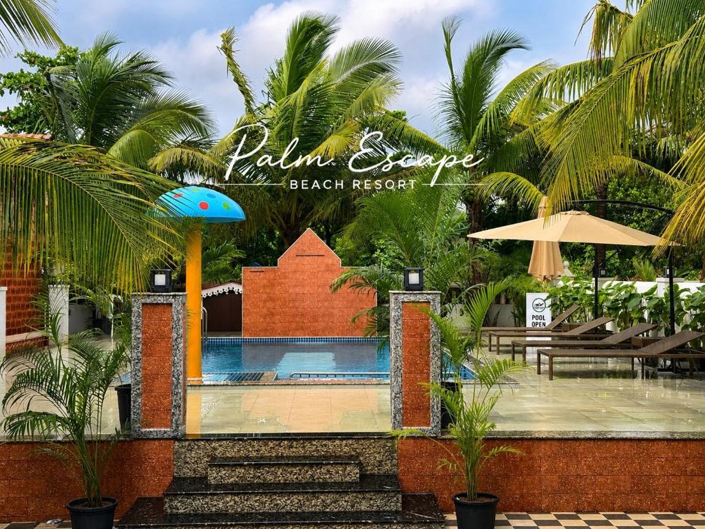 a resort with a swimming pool and palm trees at Palm Escape Beach Resort in Baga