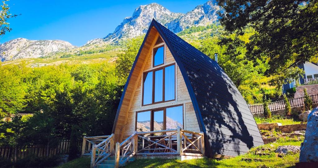 a tiny house with a large window and mountains in the background at Andi's Home in Bogë
