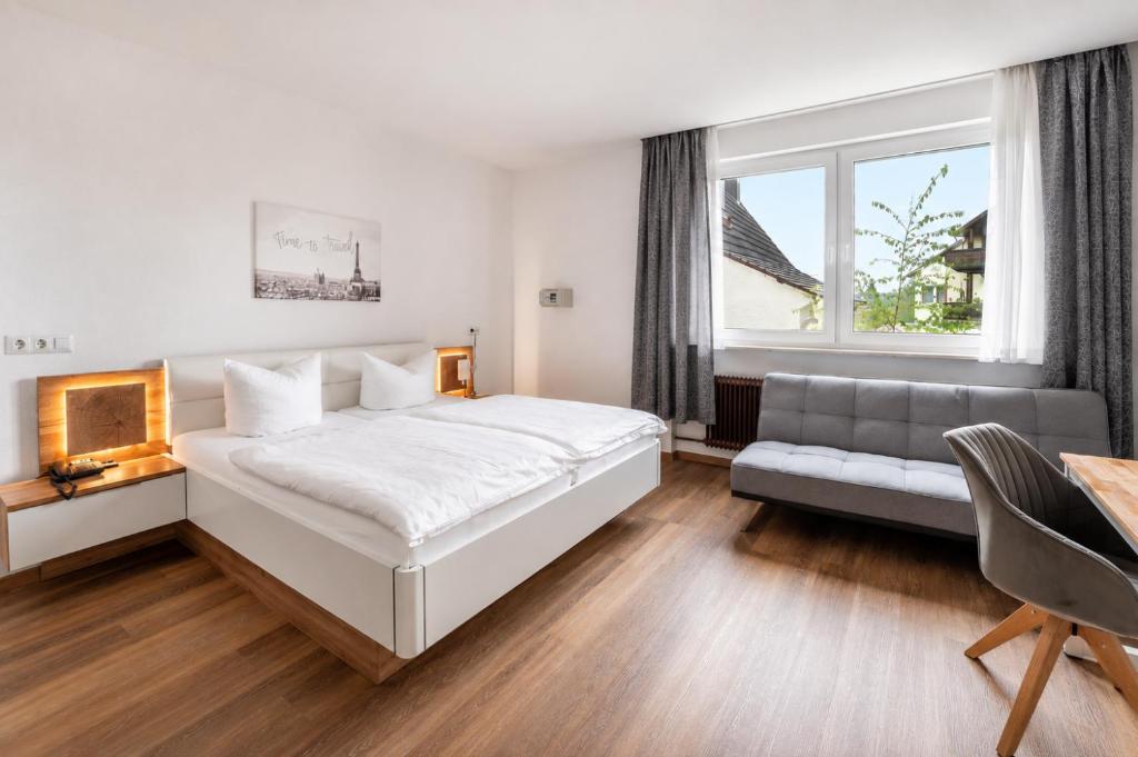 a bedroom with a large white bed and a couch at Hotel Glas Schwarzwald in Fluorn