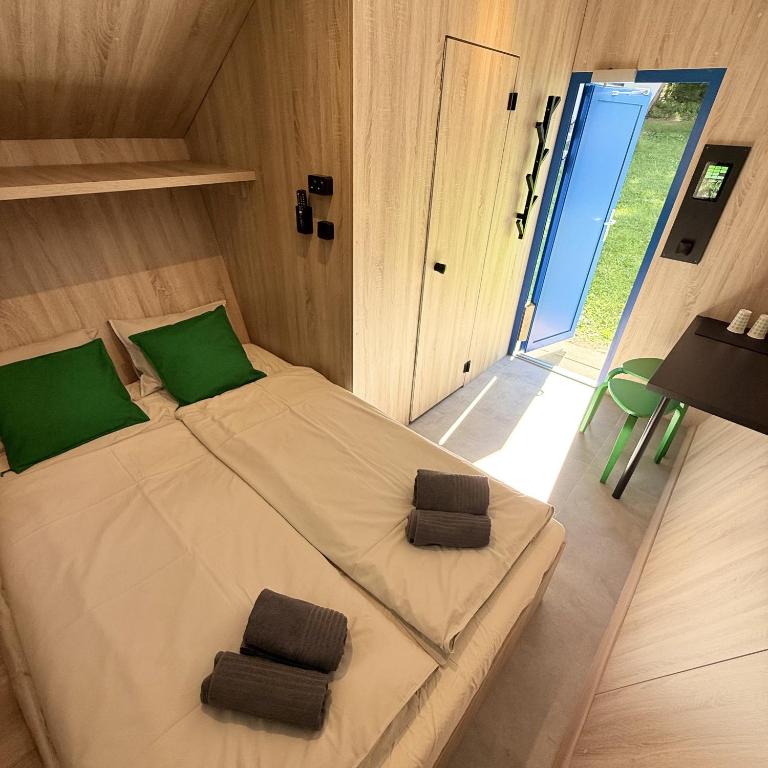 a bedroom with a large bed with green pillows at Glamping chatky in Spišské Tomášovce