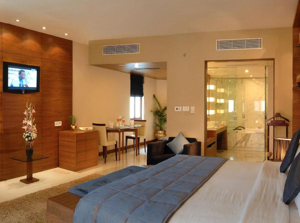 a bedroom with a large bed and a living room at Hotel Rosewood Suites Near Delhi IGI Airport in New Delhi
