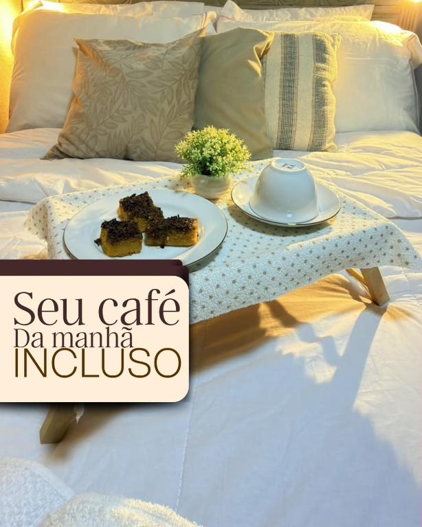 a table with two plates of food on a bed at Chalé Diamante c /AR in Volta Redonda