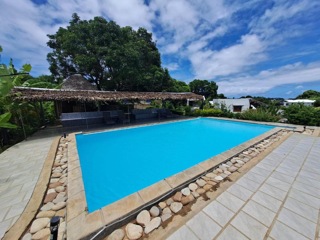 ein Swimmingpool im Garten mit einem Pavillon in der Unterkunft Mango Eden Hotel in Nosy Be