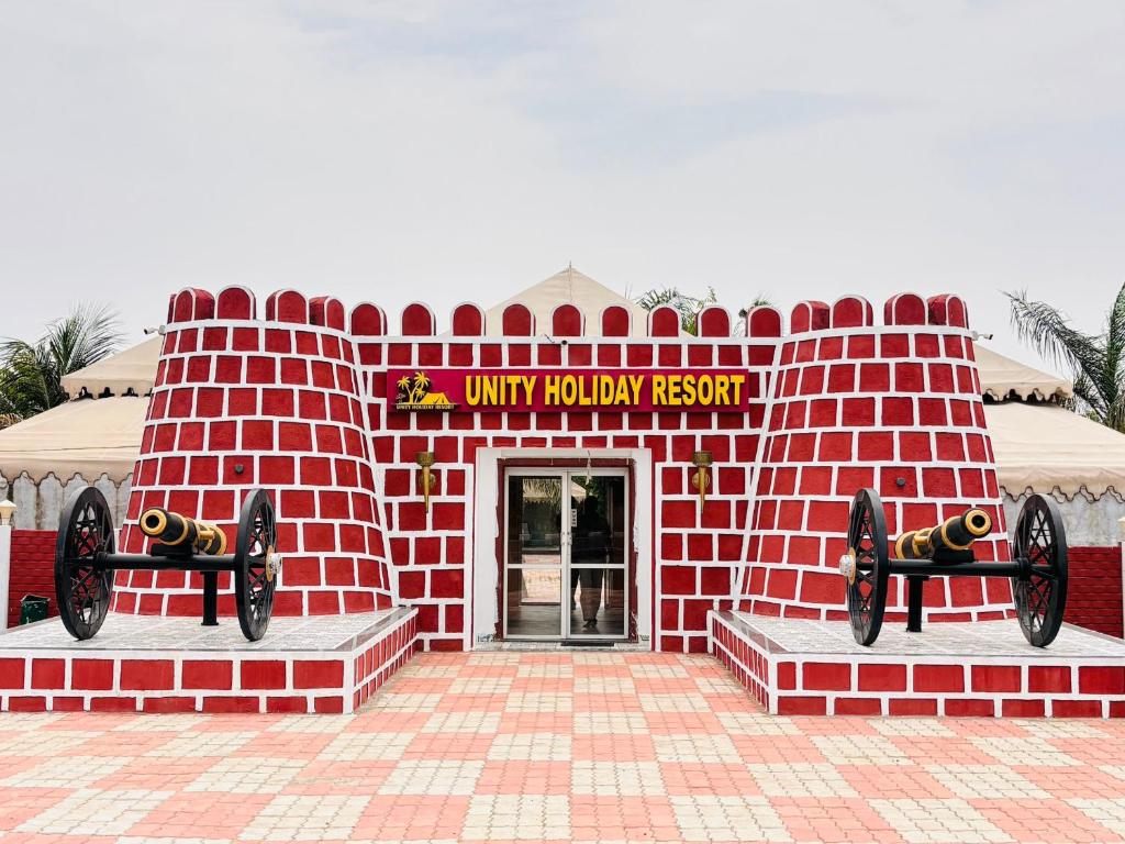 a red brick building with a sign that reads unity holiday resort at Unity Holiday Resort in Kevadia