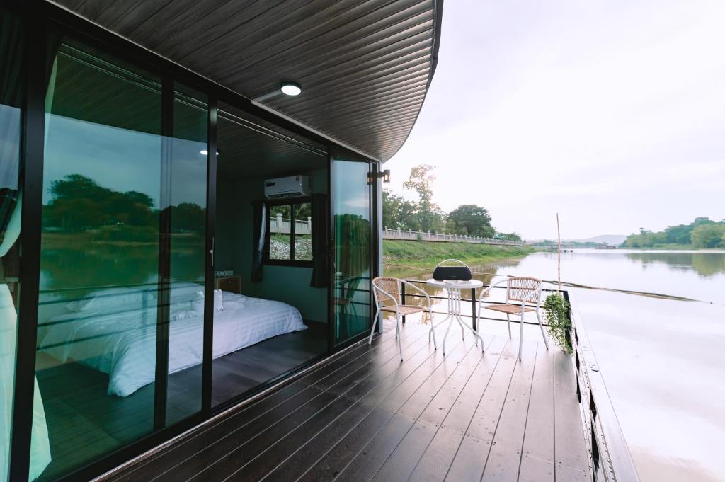a house on the water with a bed and a table at แพ River Tale Uthaithani in Ban Khok Mo