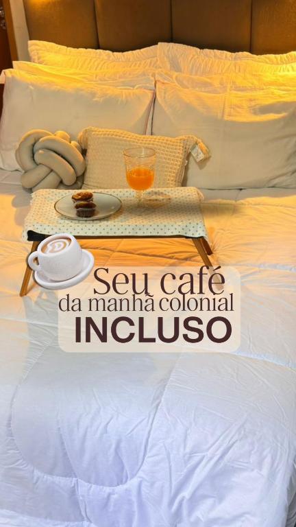 a white bed with a tray of food on it at Loft Essence in Volta Redonda