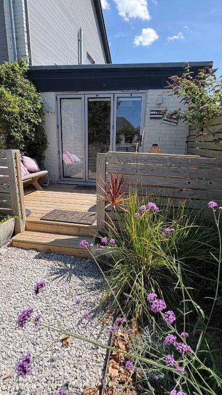 a wooden deck with a bench and some flowers at The Shack in East Wittering