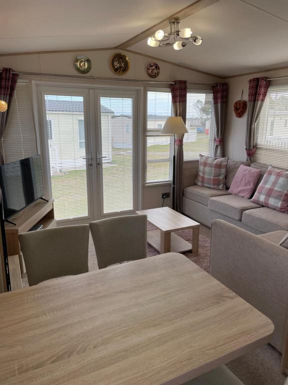 a living room with a table and a couch at Sunset View - with view of the lighthouse and a shower and bath in Lossiemouth