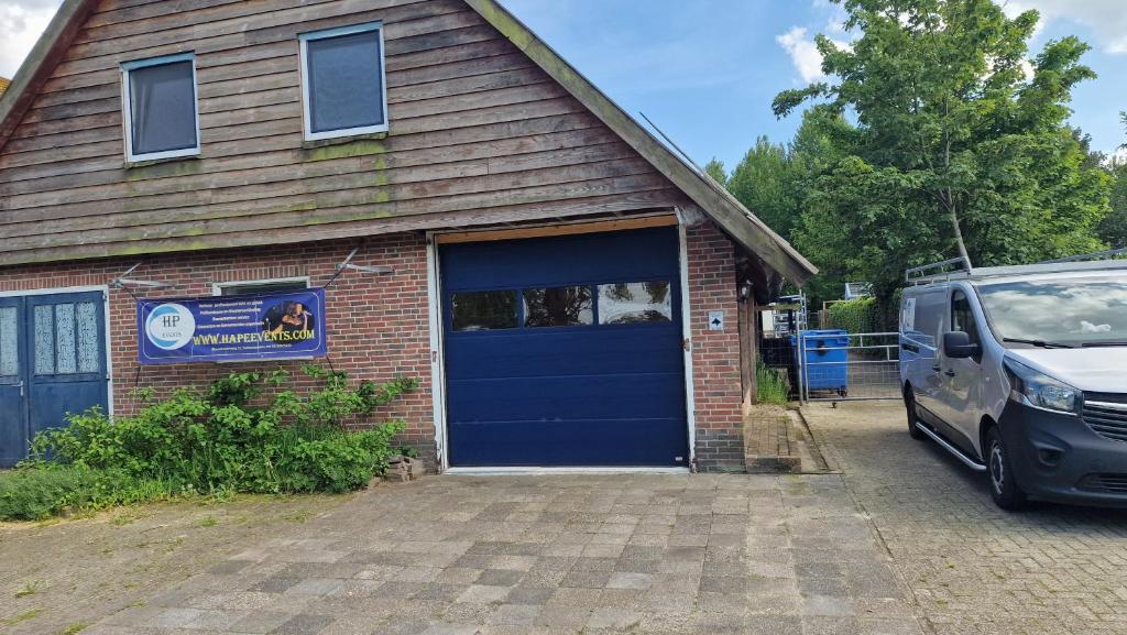 a van parked in front of a house with a blue garage at Vakantiewoning Blauhûs in Surhuisterveen