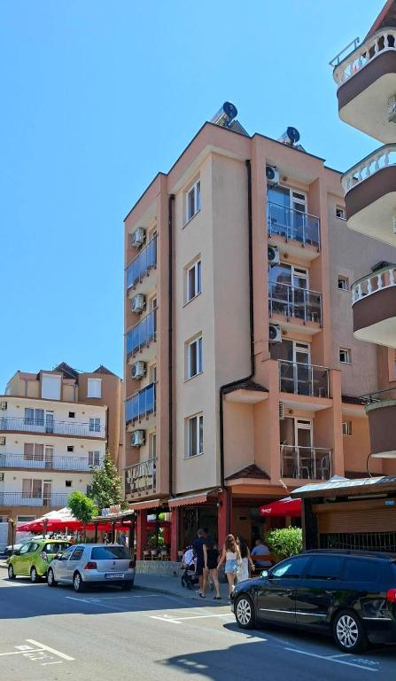 a tall building with cars parked in a parking lot at Guest House Nedelchevi in Primorsko