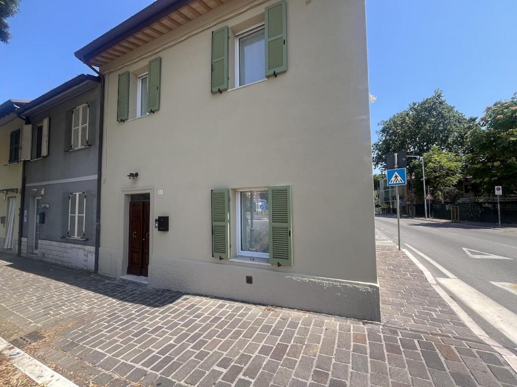 a white building with green shutters on a street at Le Port Vieux in Pesaro