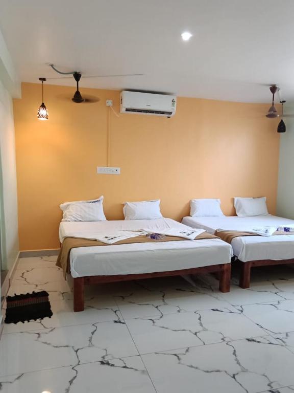 a room with two beds in a room with a wall at Relax Residency in Mandapam