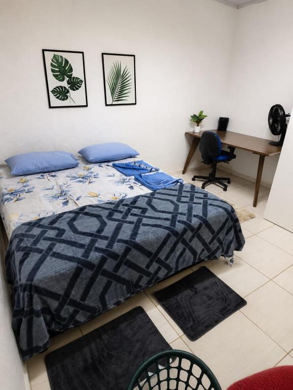 a bedroom with a bed with blue pillows and a desk at Pousada da Juh in Campo Grande