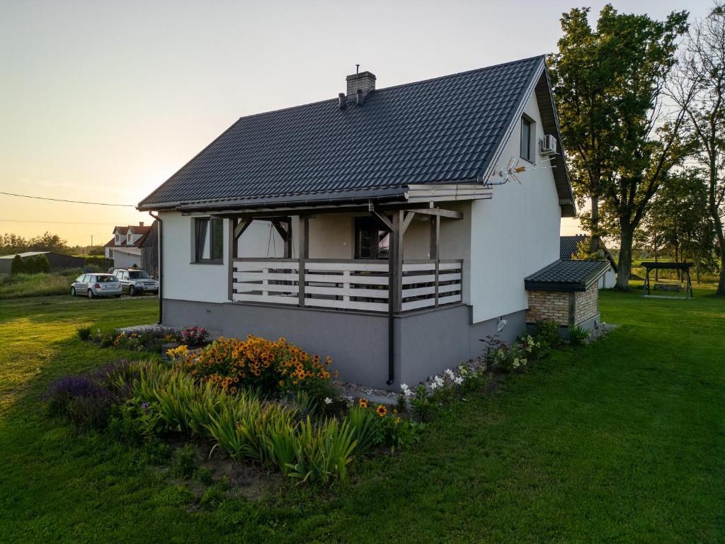 a white house with a black roof and some flowers at Ostoja Tatary Agroturystyka in Tykocin