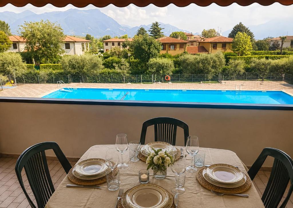 a table with glasses and plates and a pool at Residence The Yellow Fish with Pool in Manerba del Garda