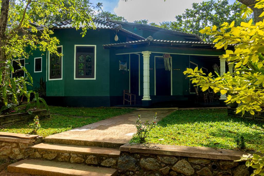 a green house with stairs in front of it at Sigiri Siesta Homestay in Sigiriya