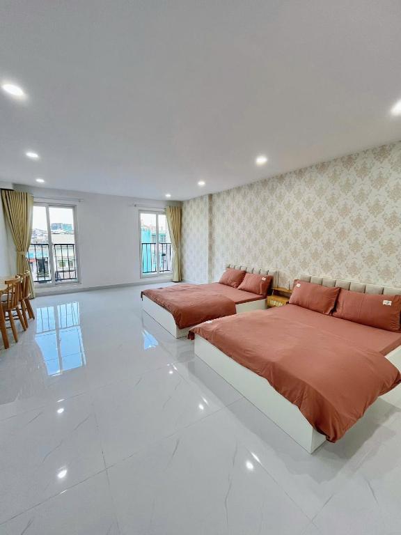 two beds in a large room with white tiles at Hạt Nắng House - Gò Vấp in Ho Chi Minh City