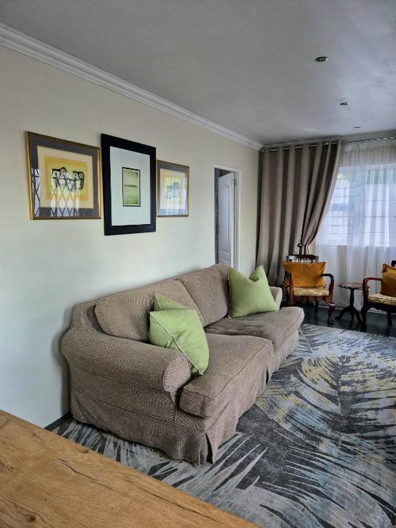 a living room with a brown couch with green pillows at Fortune Cottage in Cape Town