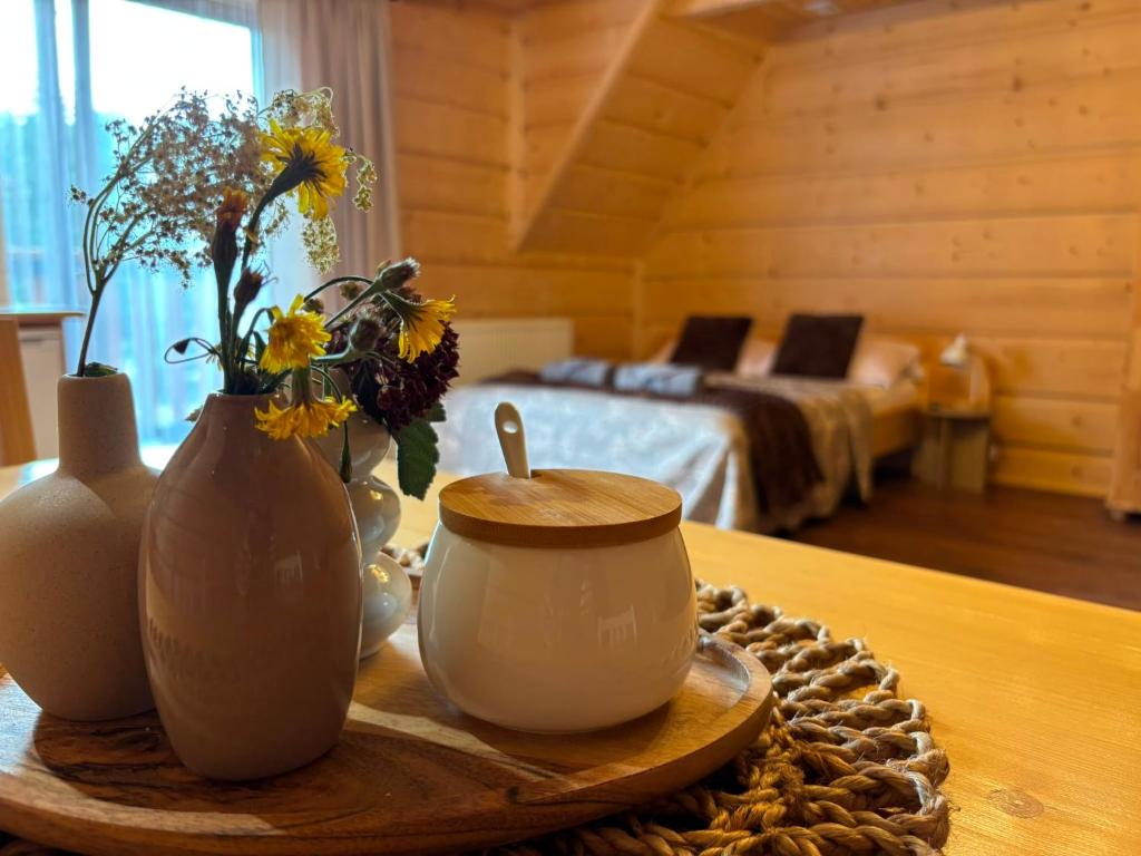 a table with vases and a cup and flowers on it at Pokoje goscinne u Jozka in Chochołów