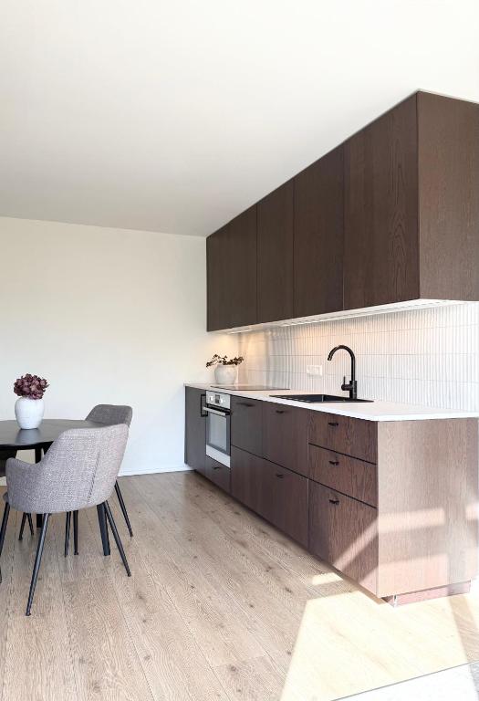 a kitchen with wooden cabinets and a table and chairs at Lonid Apartment in Höfn