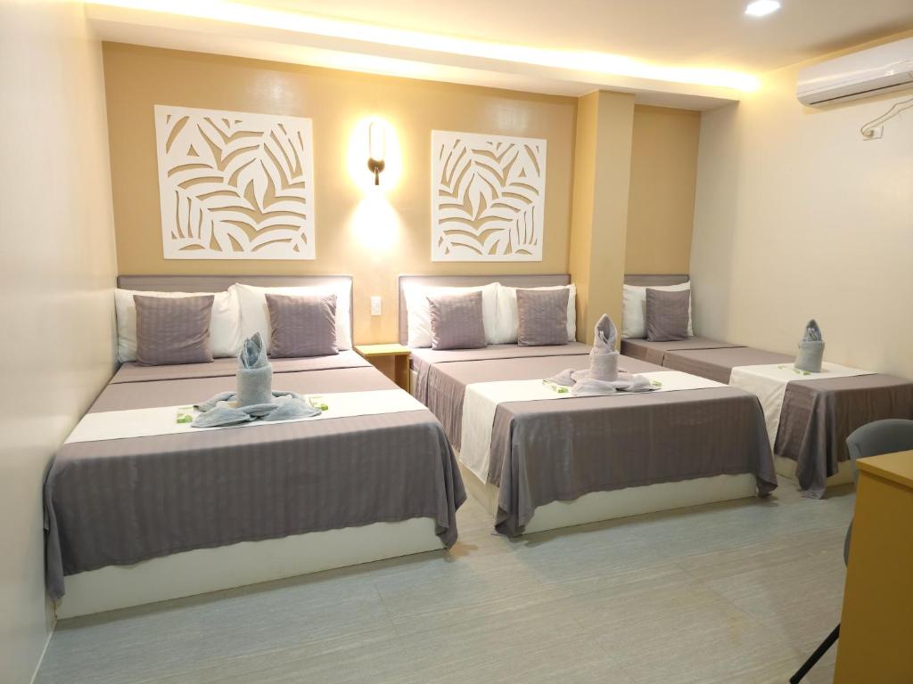 a hotel room with two beds and paintings on the wall at La Casa Princesa Inn in Puerto Princesa City