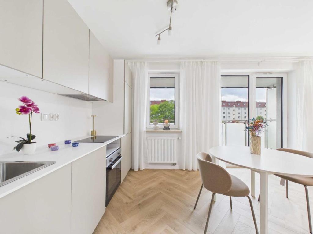 a white kitchen with a white table and chairs at Apartament HUZAR 2 in Białystok