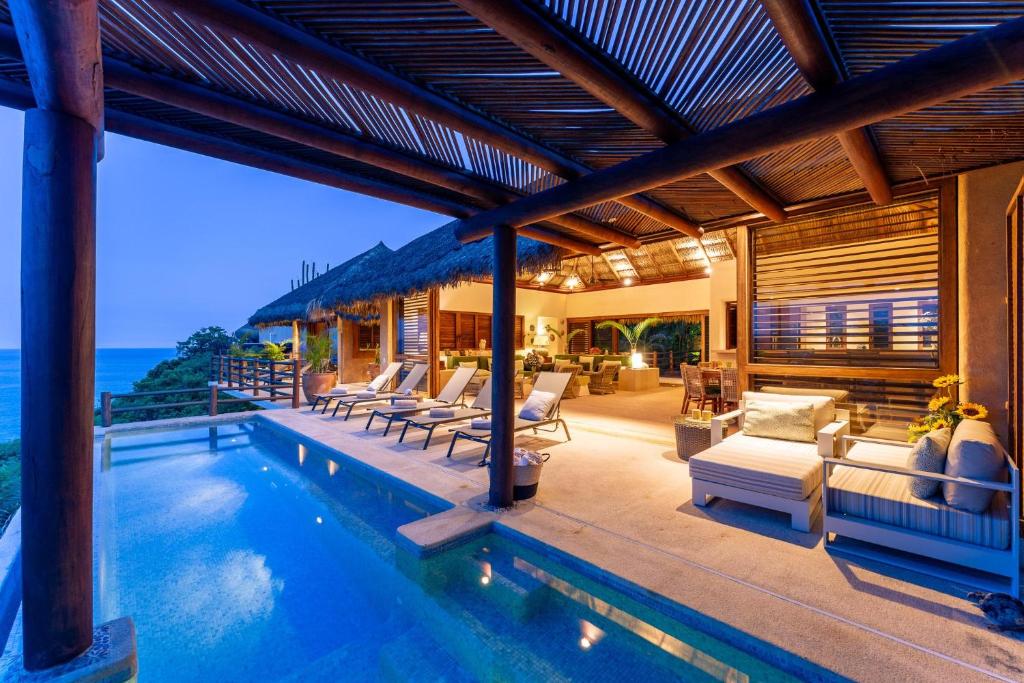 an outdoor patio with a pool and lounge chairs at 2024 - Villa Serena in Santa Cruz Huatulco