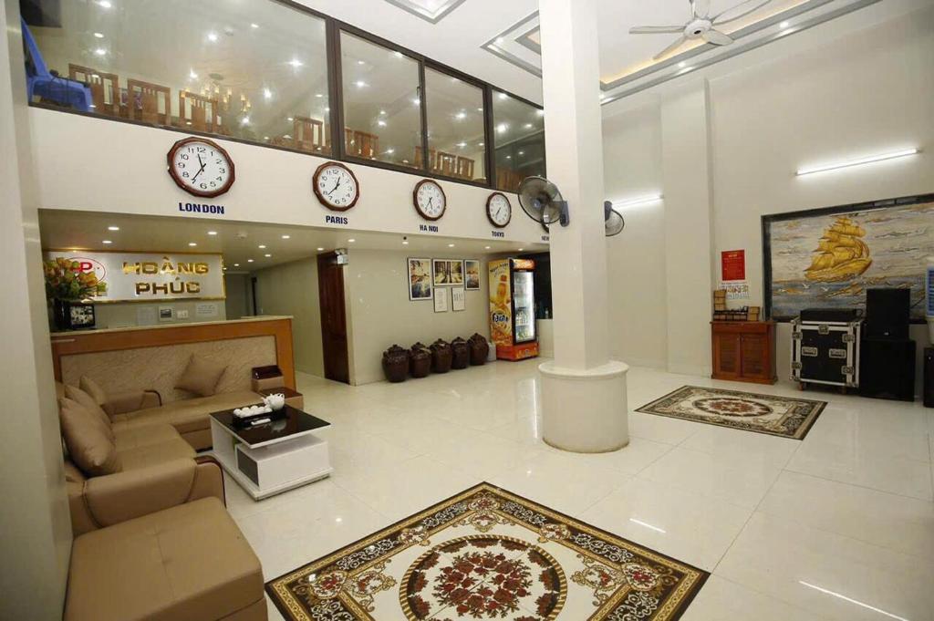 a living room with a couch and clocks on the wall at Hoàng Phúc home - restaurant in Cat Ba
