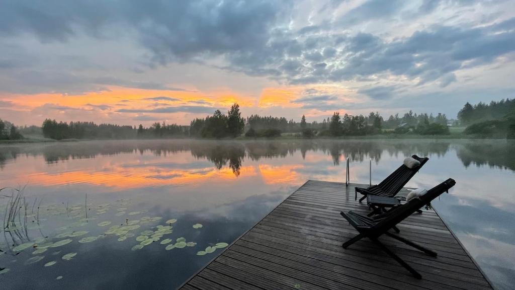 a couple of chairs sitting on a dock on a lake at Villa Narikko in Sysmä