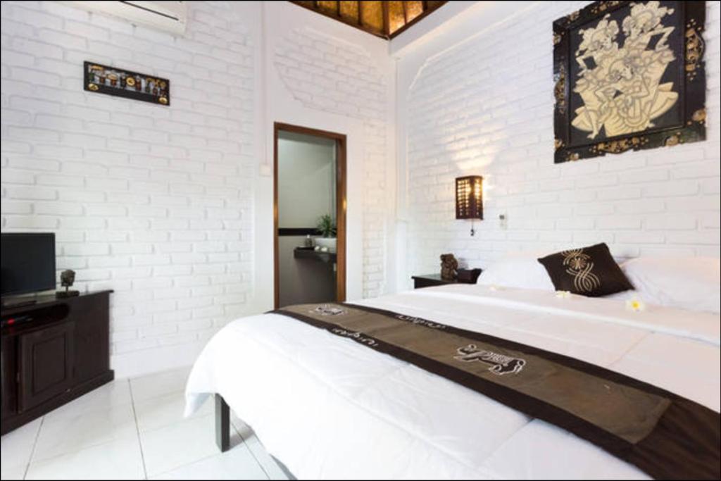 a white bedroom with a bed and a television at New Danas Canggu Guest House in Kerobokan