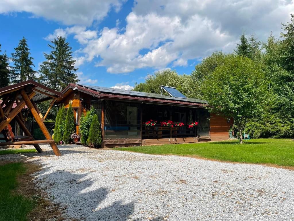 a log cabin with a gravel road in front of it at Ezüst fenyő vendégház in Borzont