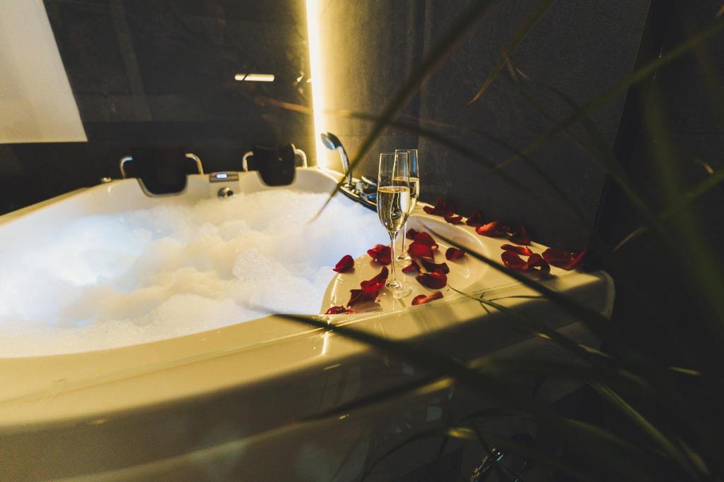 a bathtub with a glass of champagne and some roses at Jacuzzi Siesławska Top Apartment in Busko-Zdrój