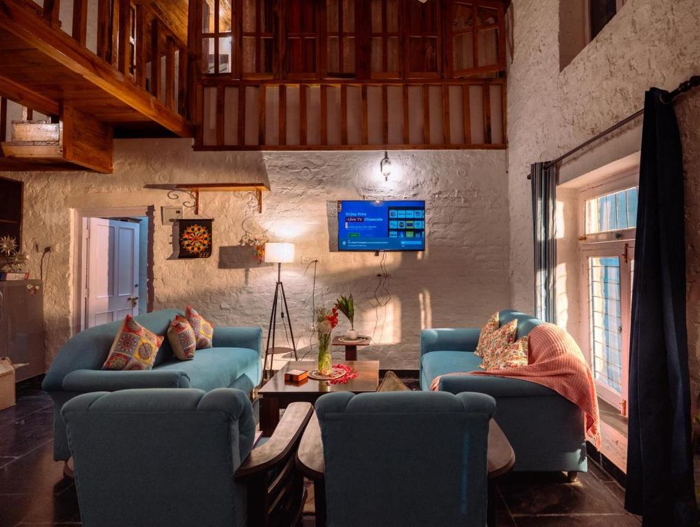a living room with two blue couches and a table at Mellowmine Premier in Kokliyal Gaon