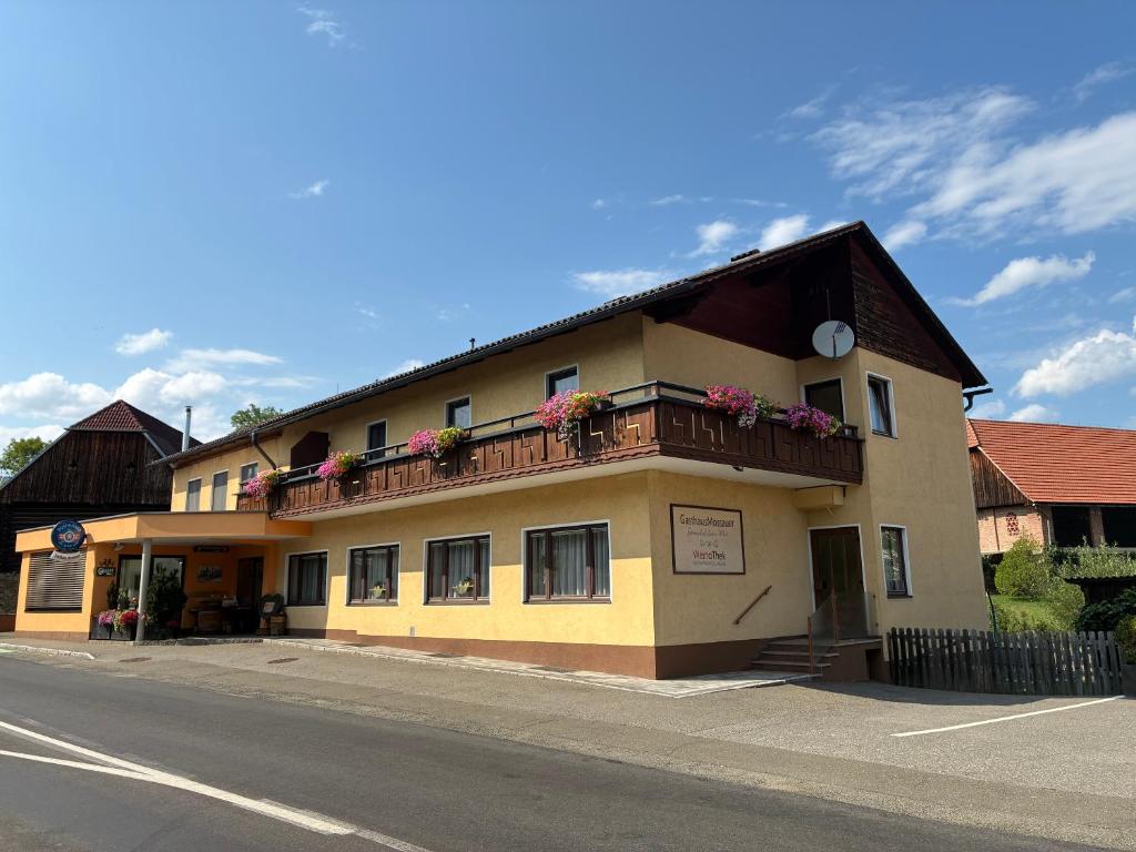 a building with a balcony with flowers on it at Gasthaus Mossauer in Feistritz bei Knittelfeld