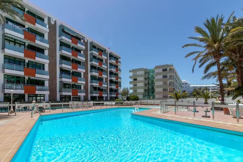 a swimming pool in front of a building at FM Beach Home - Winter Sun Apartment with Pool & Terrace in Playa del Ingles