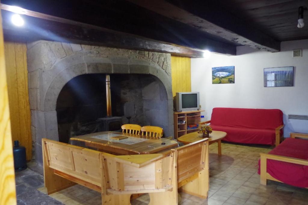 a living room with a fireplace and a red couch at Chez ellen in La Tour-dʼAuvergne