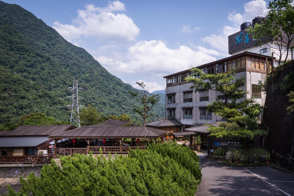 a hotel building with a mountain in the background at Wulai SungLyu Hot Spring Resort in Wulai