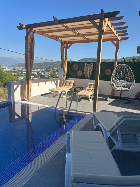 a swimming pool with a wooden pergola and chairs on a roof at Villa Metehan in Kumluca