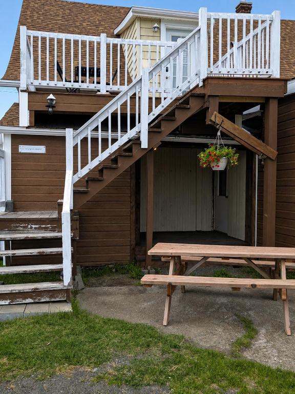 a wooden porch with a deck and a bench at Le Pignon Douillet in Sainte-Anne-des-Monts