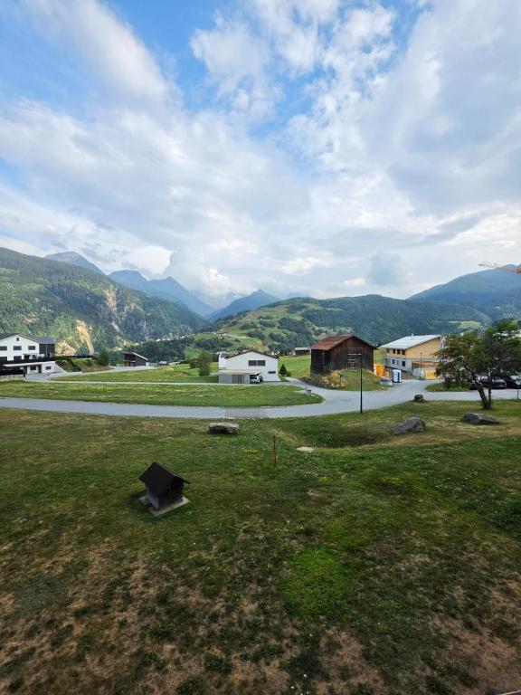 a field with a road and mountains in the background at Utoring Acletta B 27 in Disentis
