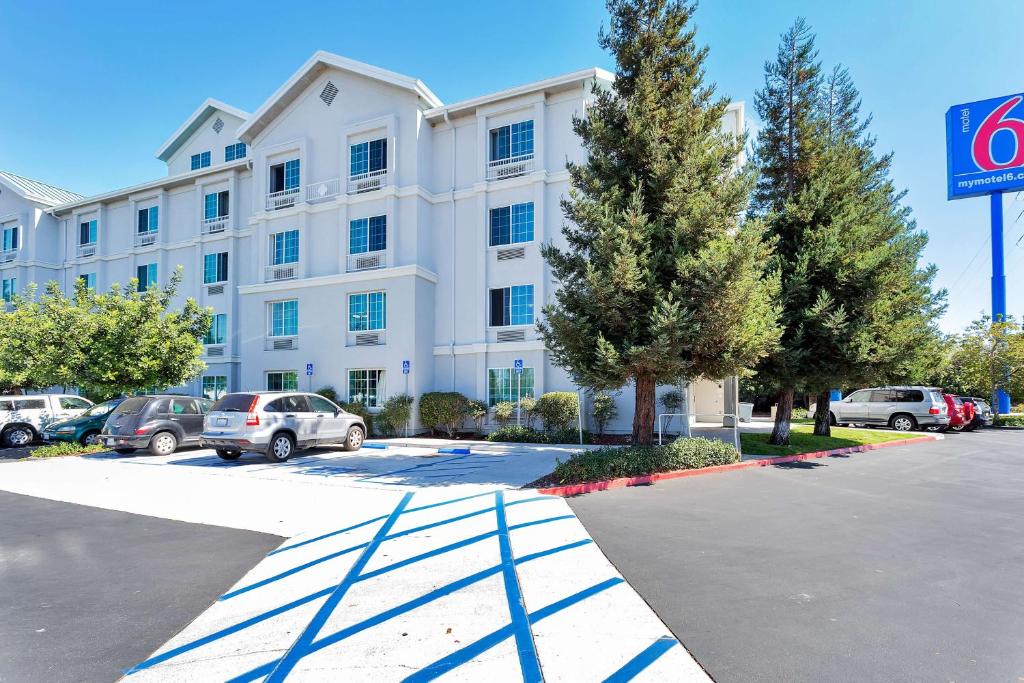 un gran edificio blanco con coches aparcados en un aparcamiento en Motel 6-Belmont, CA - San Francisco - Redwood City, en Belmont