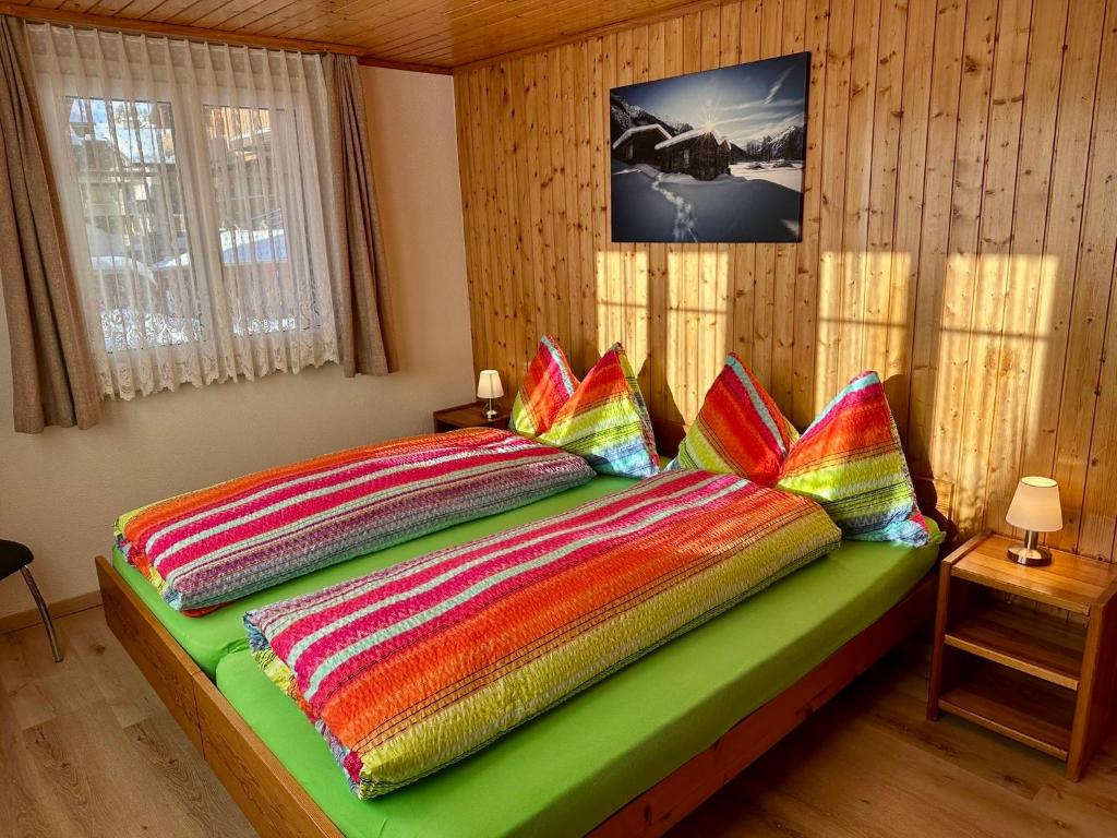 a bedroom with a bed with colorful blankets and pillows at Chalet Alpenheim 1 OG in Bettmeralp