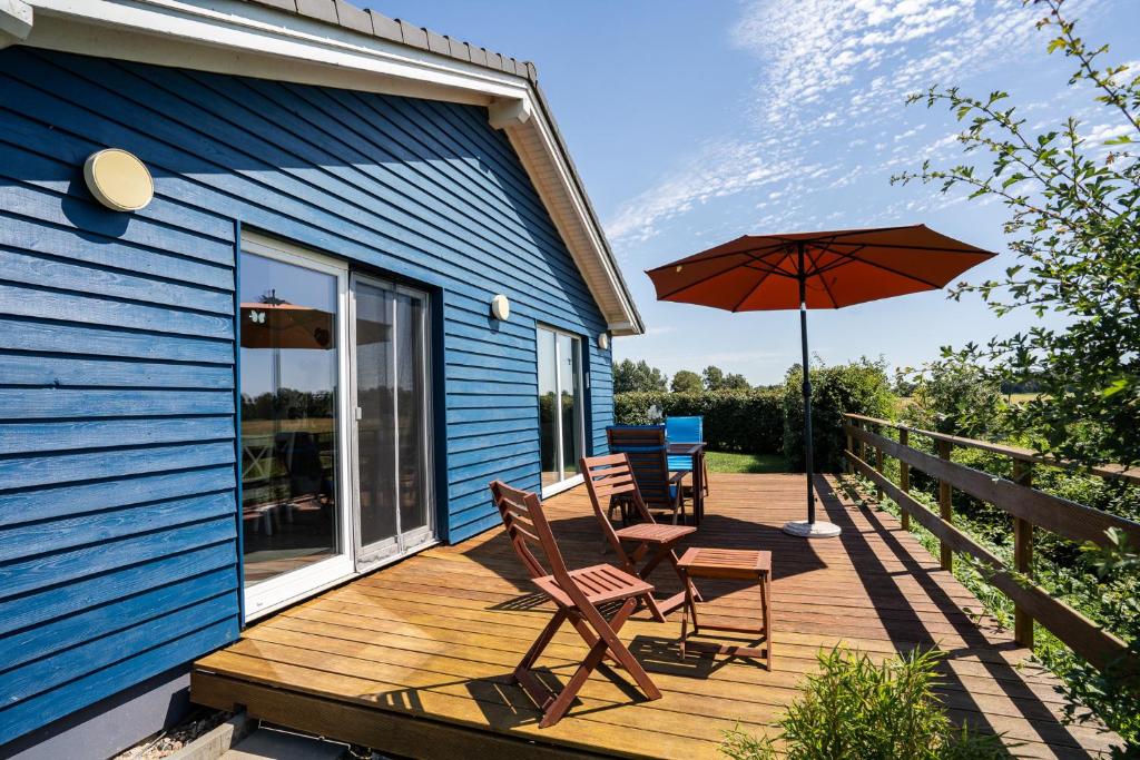 a wooden deck with two chairs and an umbrella at Haus Freija in Sehestedt