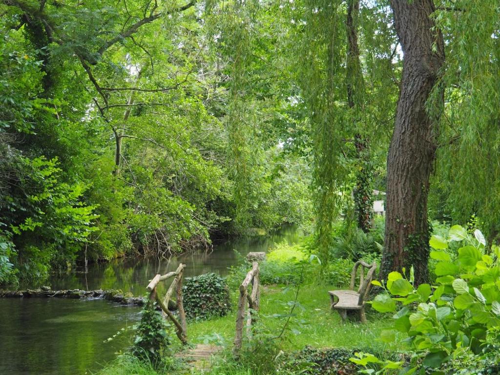 a park with a bench next to a river at Maison du Verger in Brosville