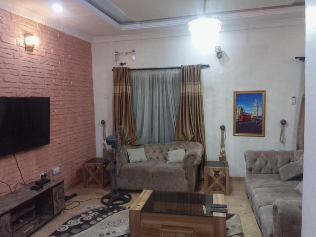 a living room with a couch and a flat screen tv at Service Apartment in Okunola
