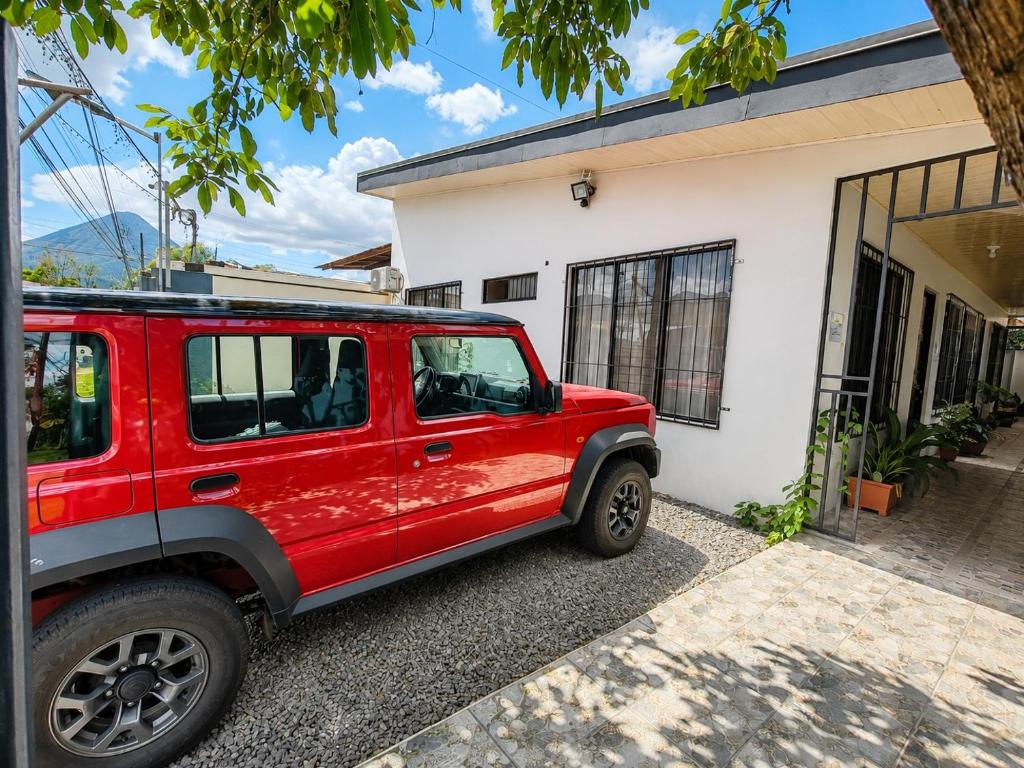 a red jeep parked in front of a house at Butterfly Apartments La Fortuna in Fortuna