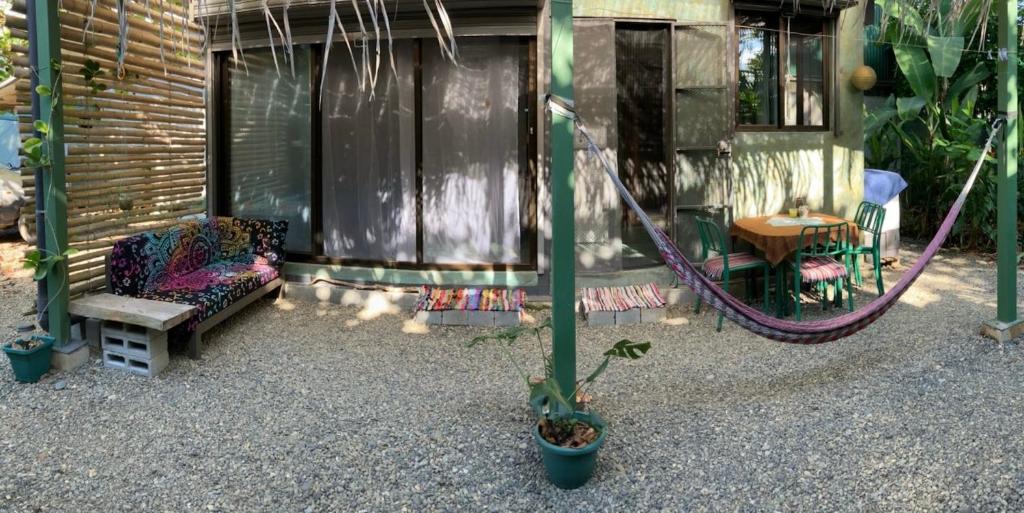 a porch with a bench and a swing and a table at Green TinyHome 1 in Uvita