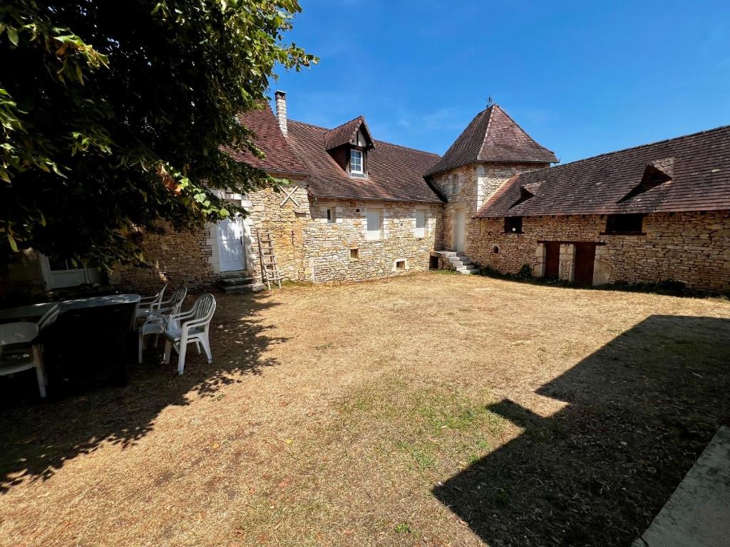 an old stone building with two chairs in the yard at La Maison de Renée in Sainte-Eulalie-dʼAns